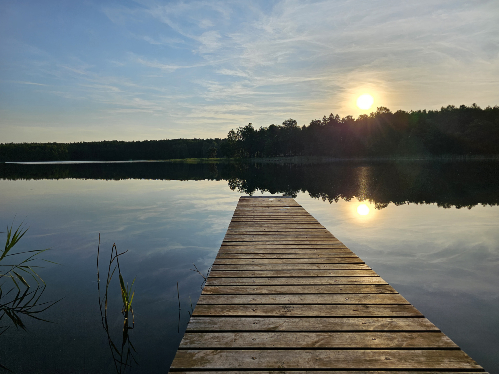Holzsteg zu einem See in der Abendsonne